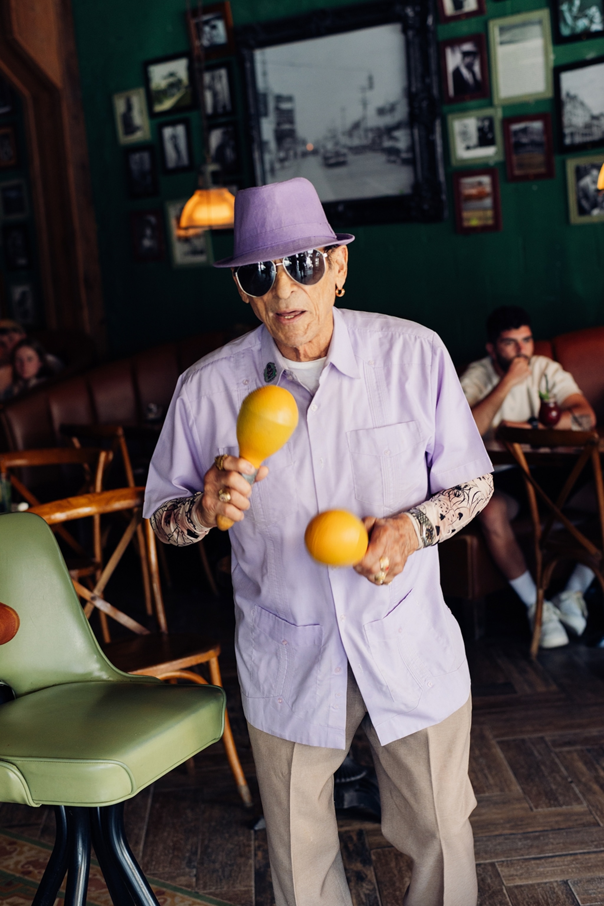 Man holding maracas dancing while wearing a hat and sunglasses